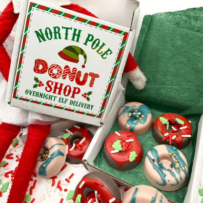 Box of 4 handmade red and green min donut soaps in a box that says 'North Pole Donut Shop'  Overnight elf delivery with Christmas themed decorations on box.