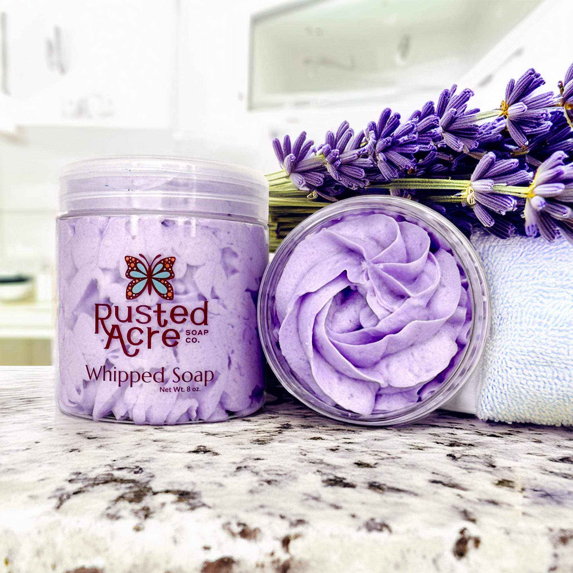 Two jars of lavender whipped soap from rusted acre soap company in a bathroom scene.