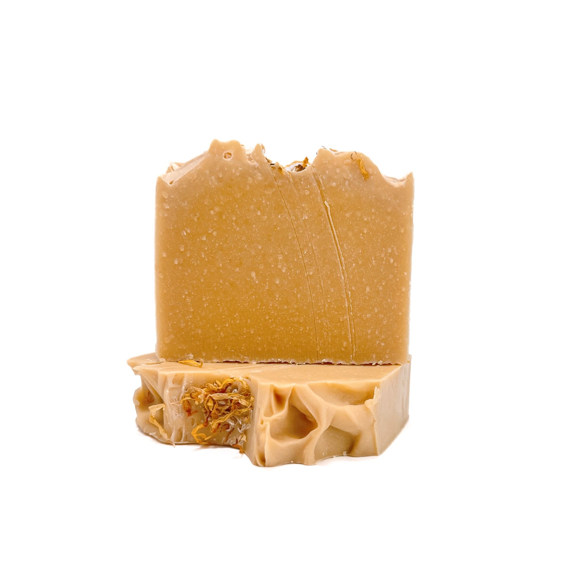 Two bars of lemon cupcake handmade soap, deep yellow in color, from Rusted Acre Soap Co. One lying flat, one upright on top.