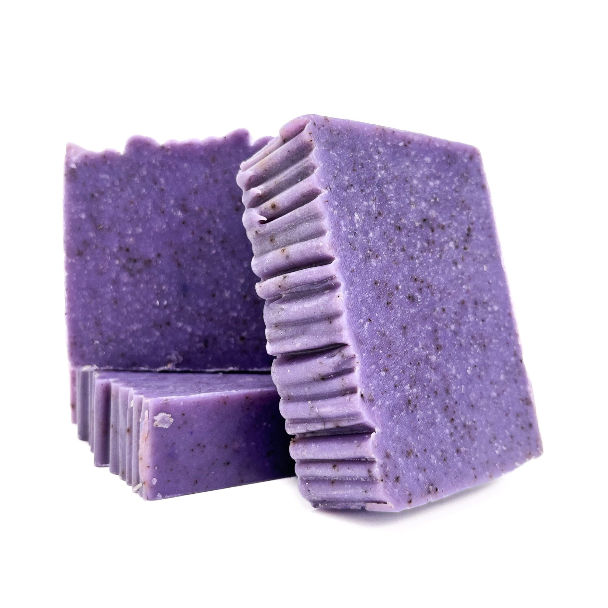 Three bars of lilac purple handmade soap from Rusted Acre Soap Co. One lying flat and two upright to show texture.