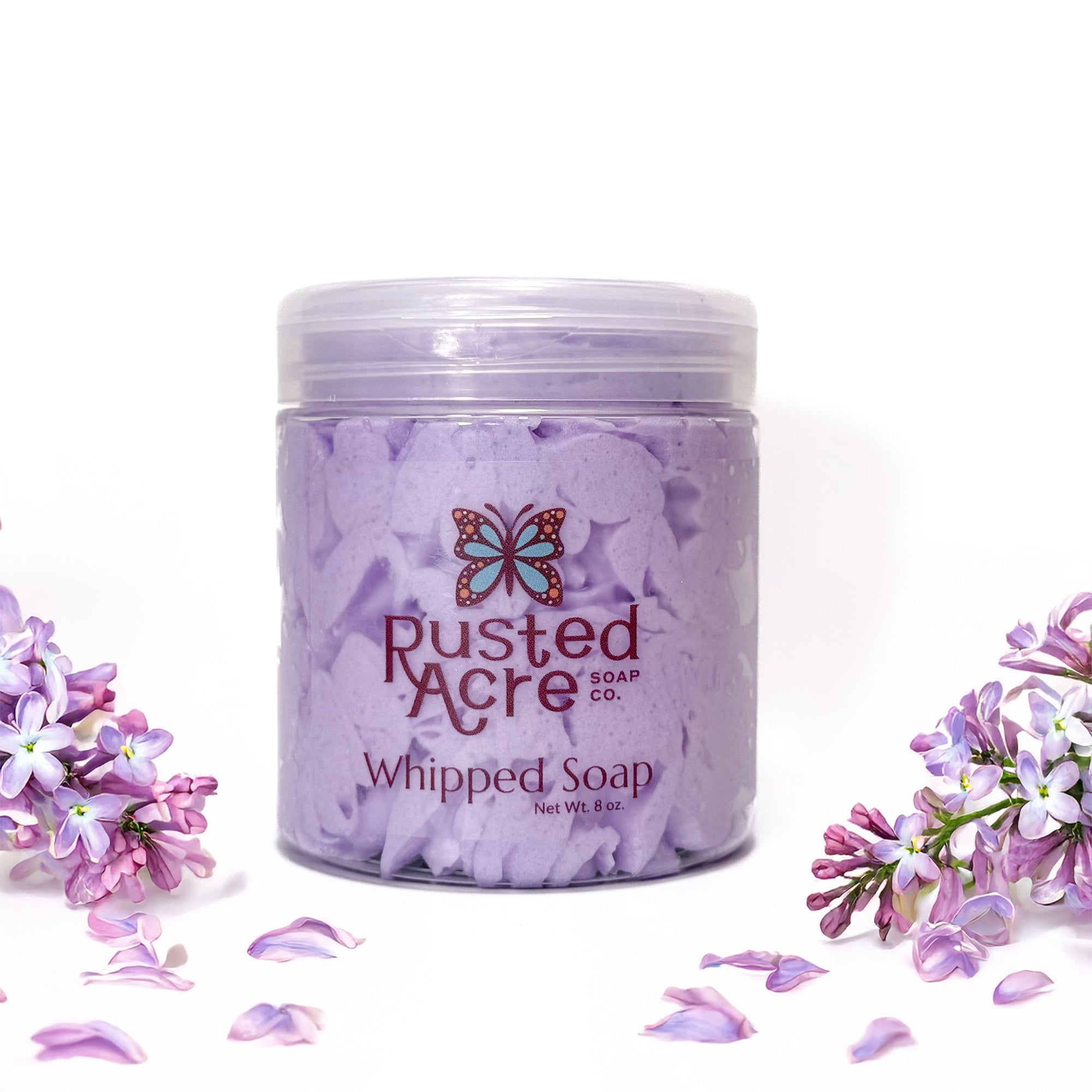 Jar of Rusted Acre Soap Company's vegan lilac whipped soap. Purple soap in a reusable plastic jar in a lifestyle setting. 