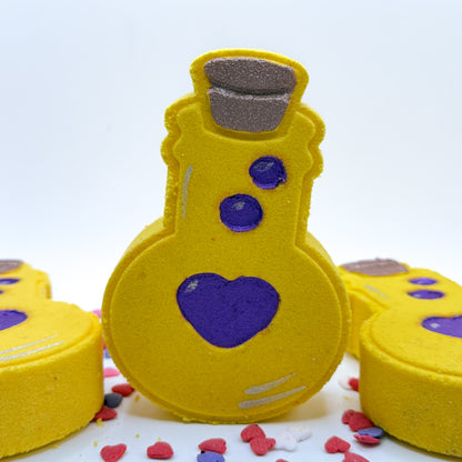 Hand painted yellow love potion bath bomb with purple hearts on a white background. 