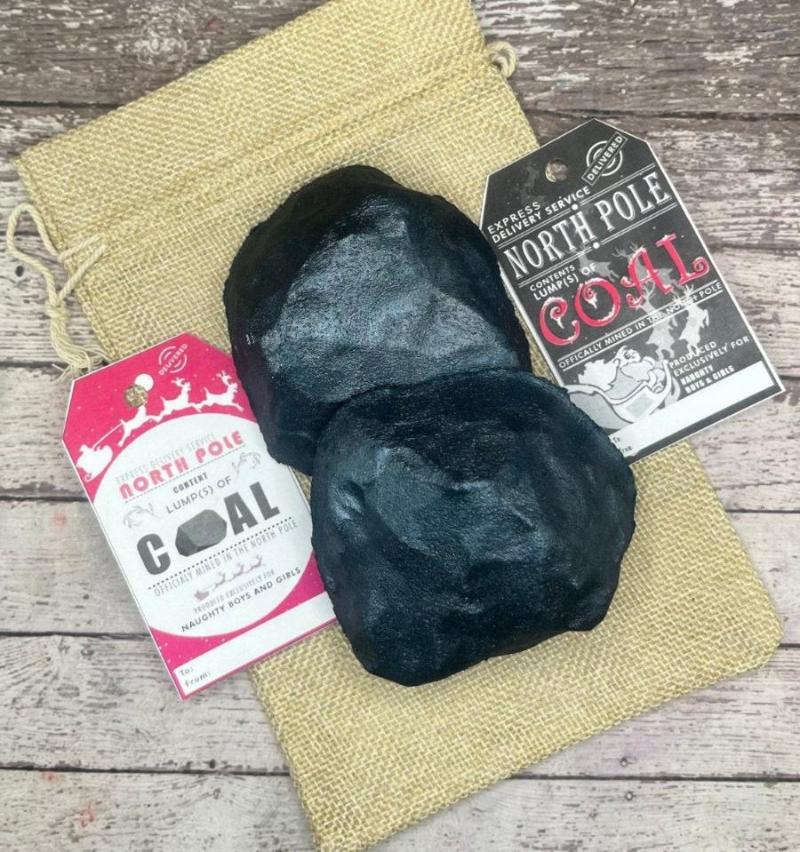 Two lumps of coal hand-painted black. Displayed on a canvas bag with gift tags on each side mentioning coal from the north pole.
