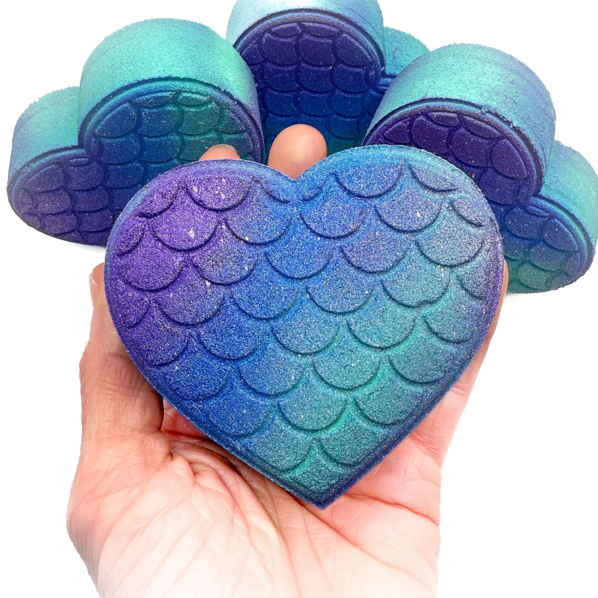 Mermaid heart bath bombs made by Rusted Acre Soap Company in hand.