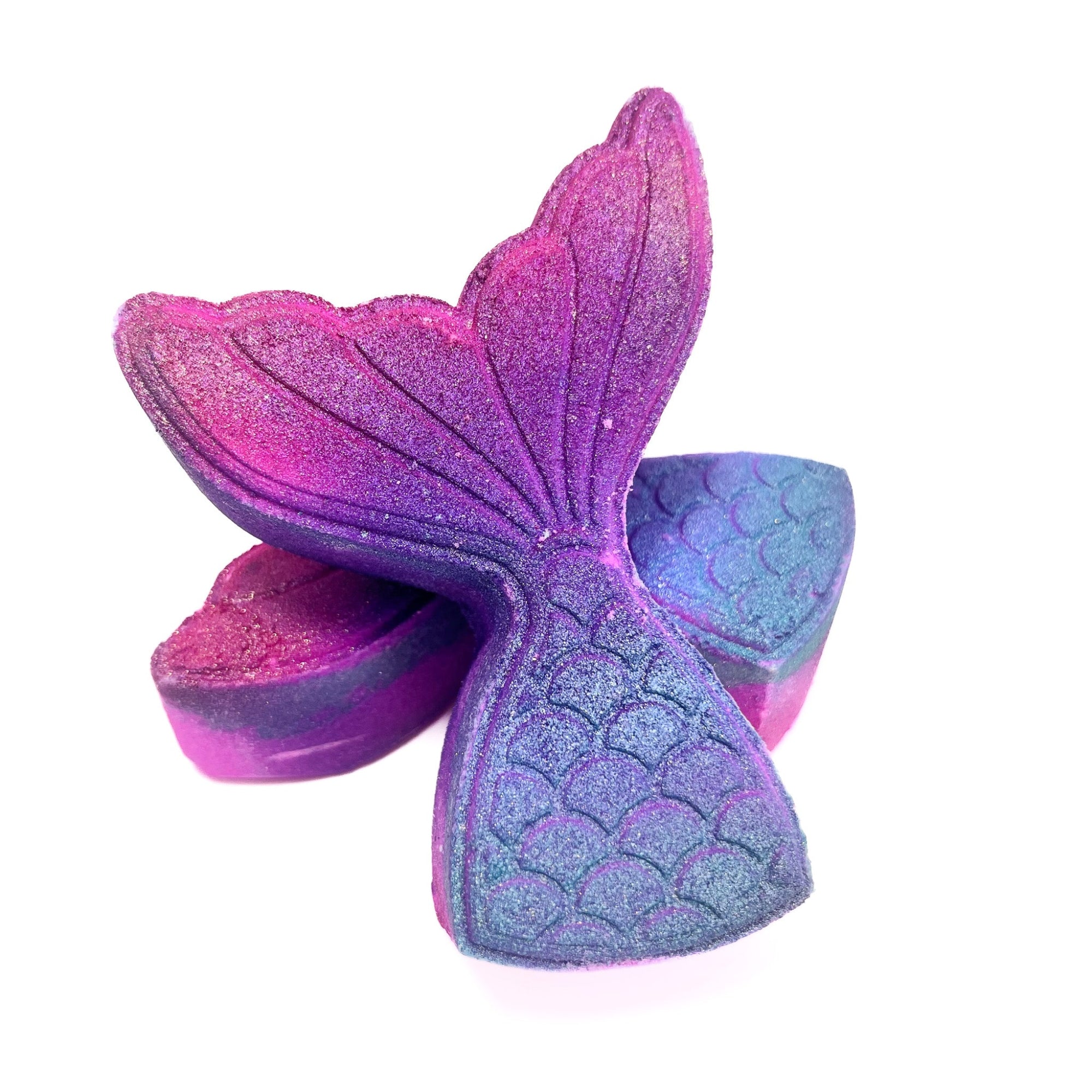 Two mermaid tail bath bombs from Rusted Acre Soap Co. One lying flat and one leaning on it just for fun!