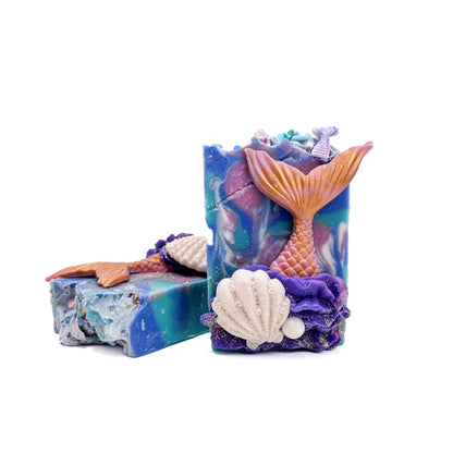 Two bars of Mermaid Tail handmade soap from Rusted Acre Soap Co.. A clam shell, a pearl, and a mermaid tail soap embed on the front.