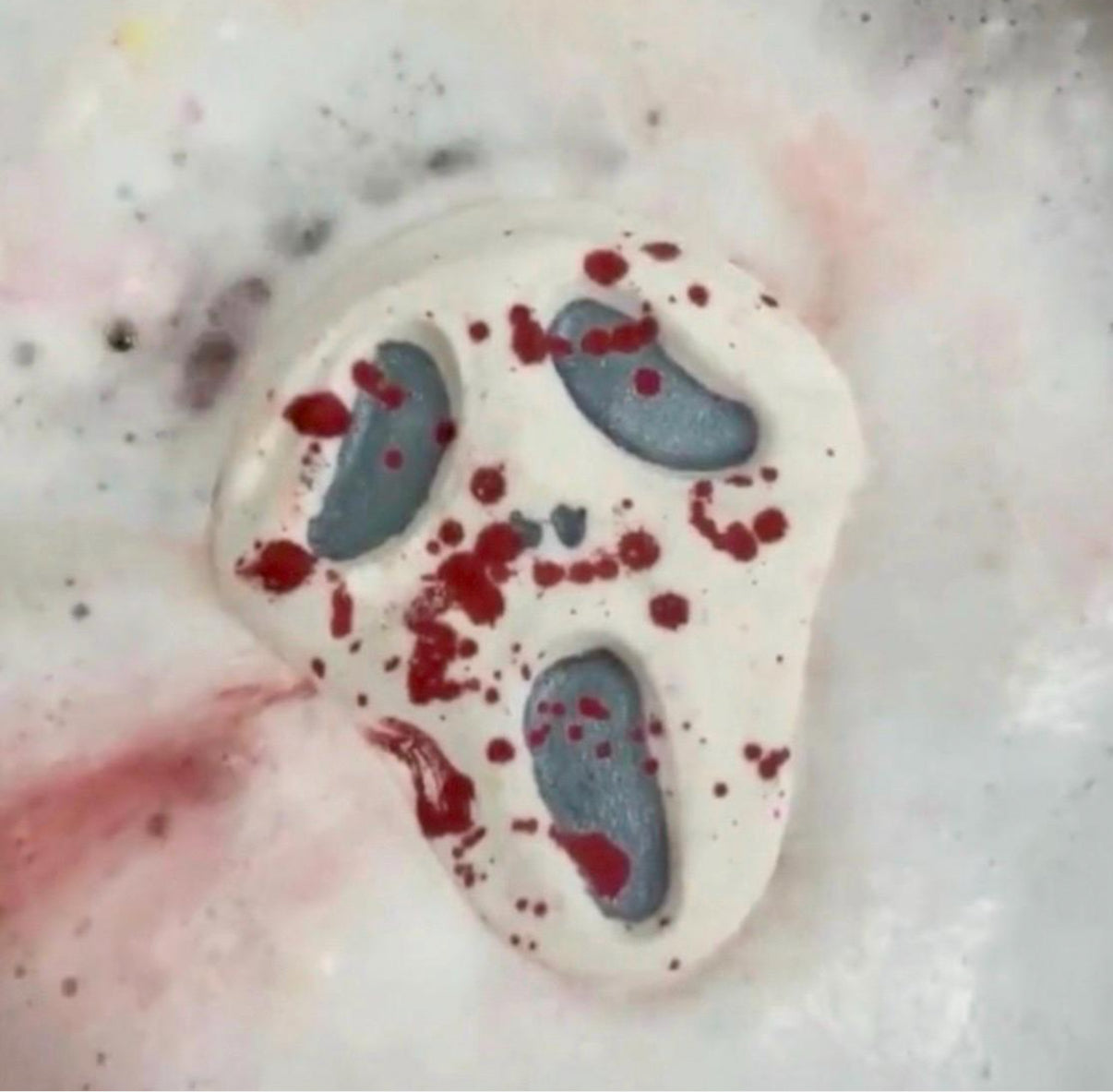 Midnight Caller horror-inspired bath bomb fizzing in the water, releasing red splatter colors and dark accents.