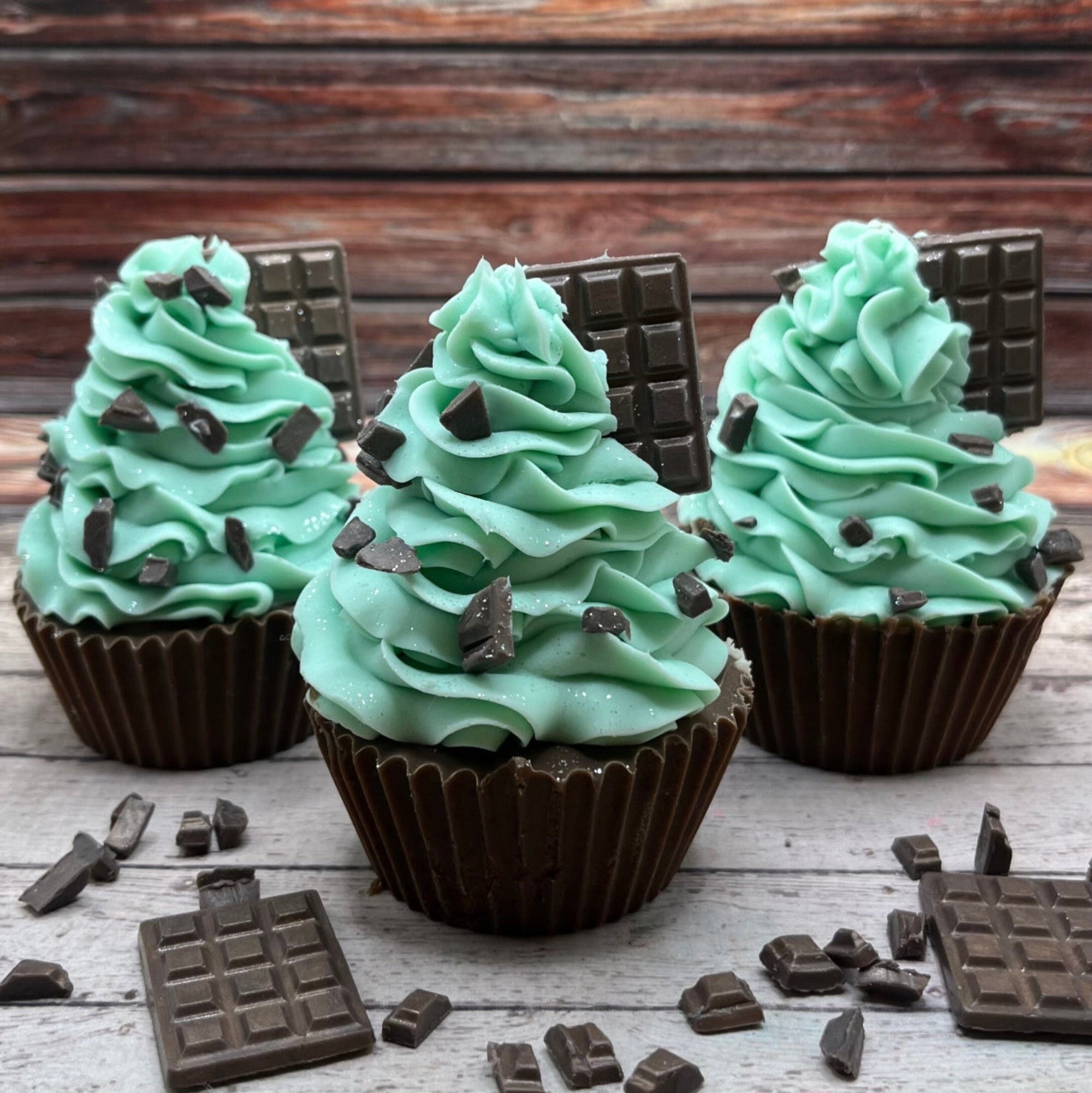 Three mint chocolate cupcake soaps being delayed on a rustic wood background. Cupcake soaps make by Rusted Acre Soap Co