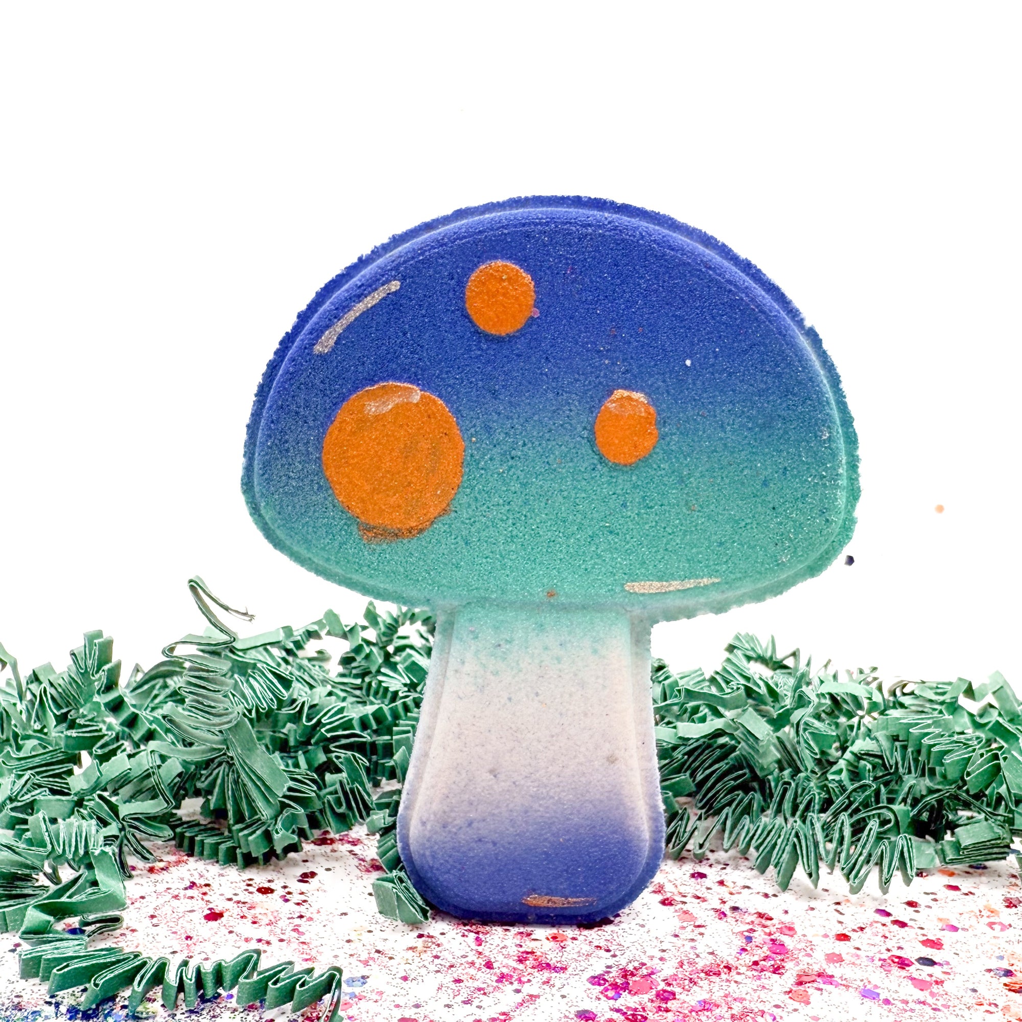 Colorful mushroom-shaped bath bomb with blue cap and orange spots on a white background. 