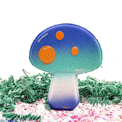 Colorful mushroom-shaped bath bomb with blue cap and orange spots on a white background. 