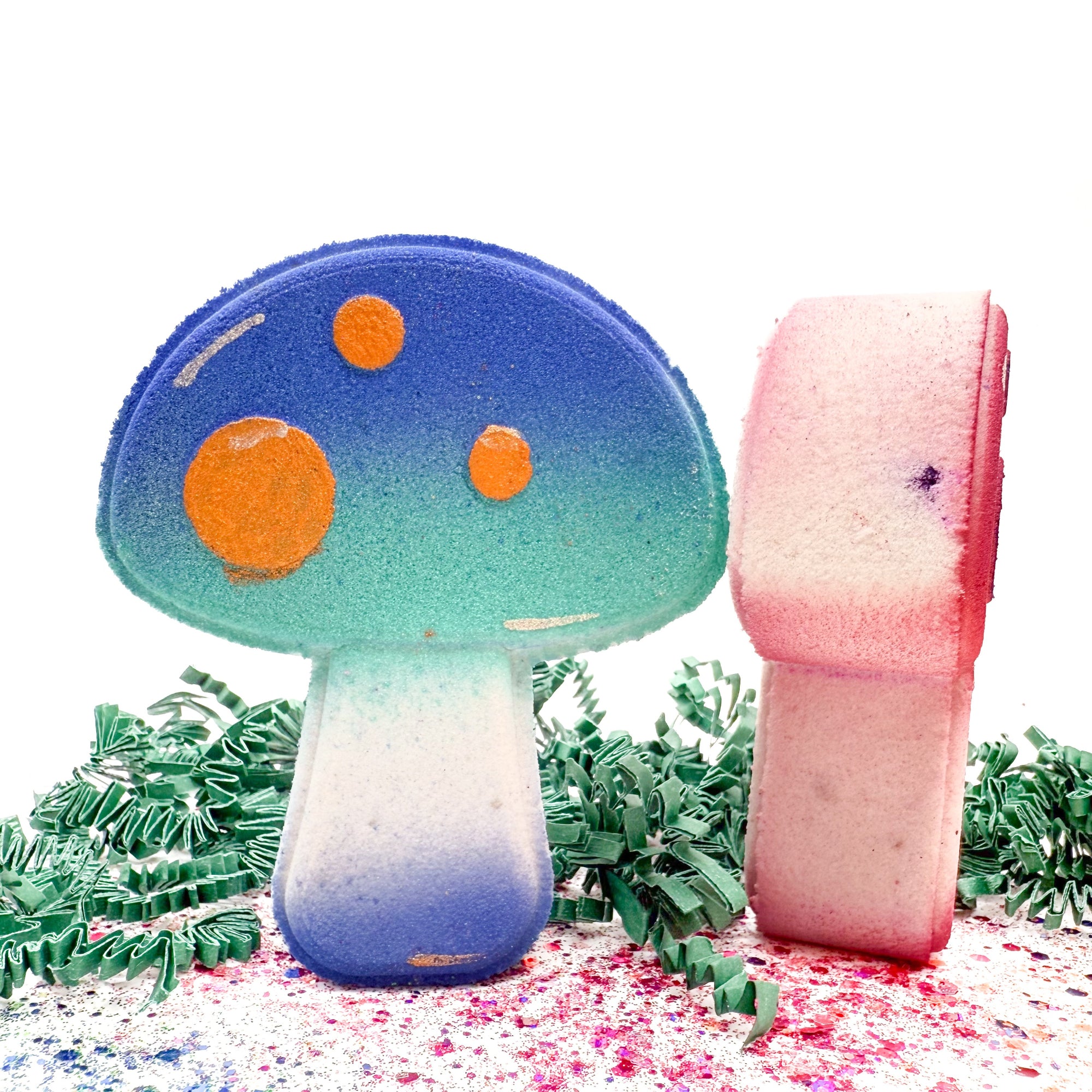 Colorful mushroom-shaped bath bombs with greenery on a white background
