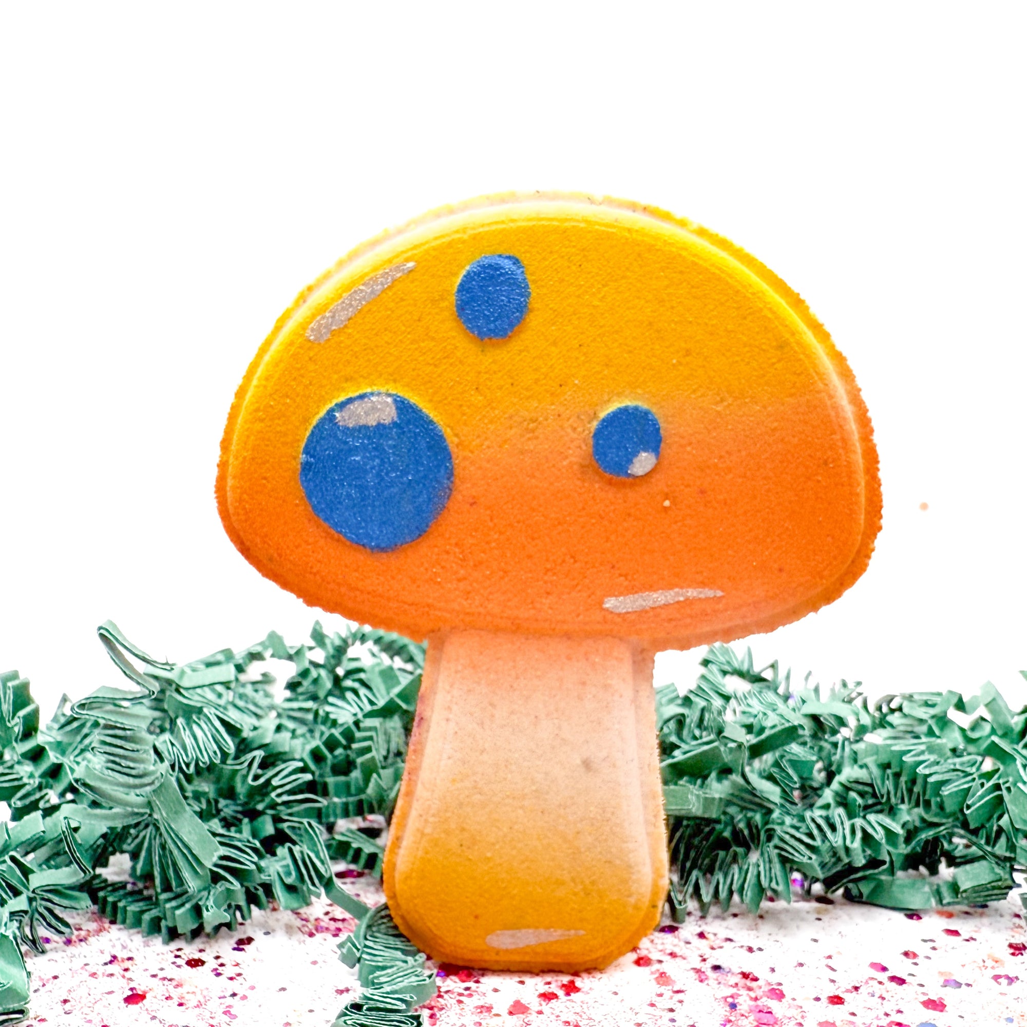 Yellow mushroom-shaped bath bomb with blue spots on a white background