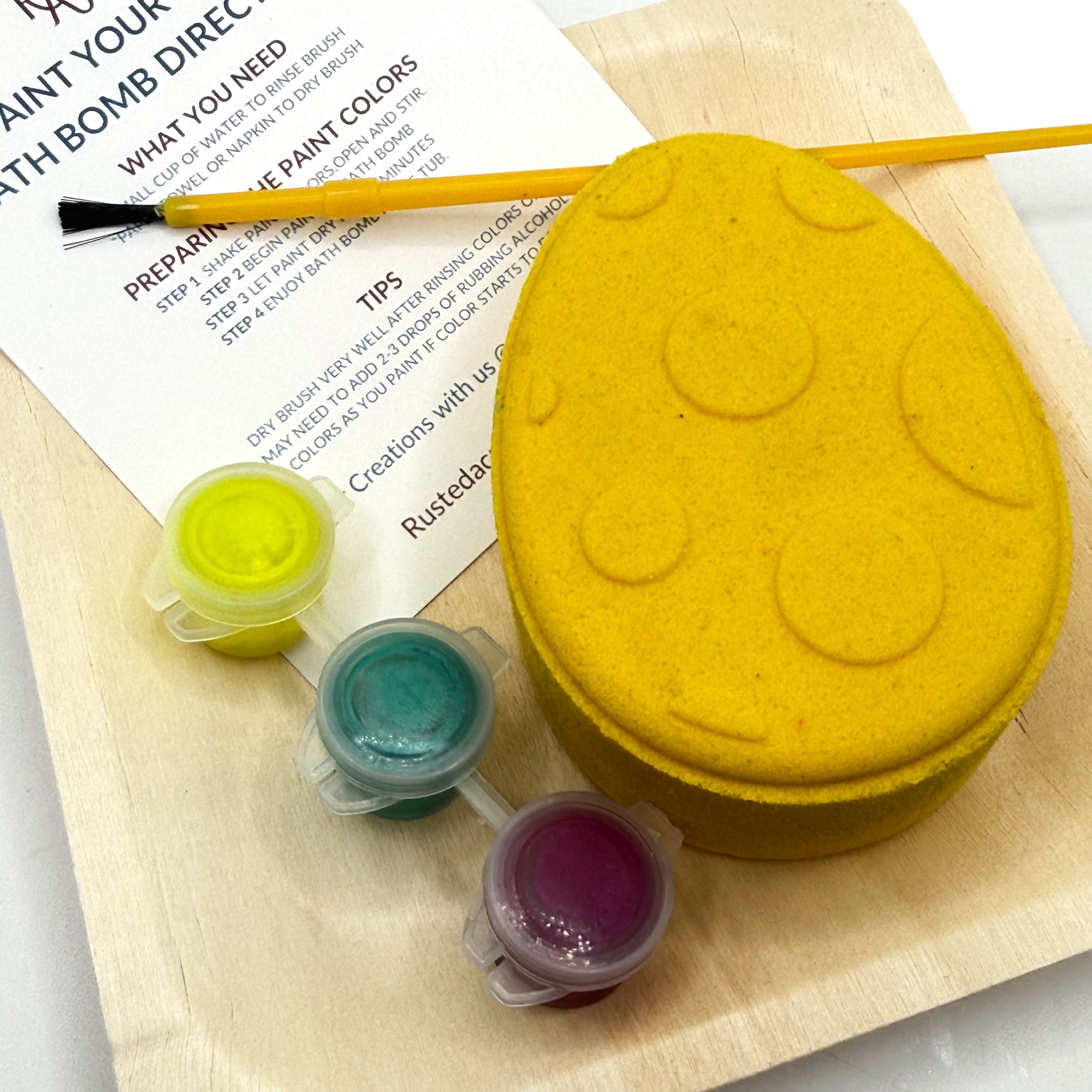 One yellow Easter Egg bath bomb kit with paint containers and a brush on a white background hand made by Rusted Acre Soap Co.