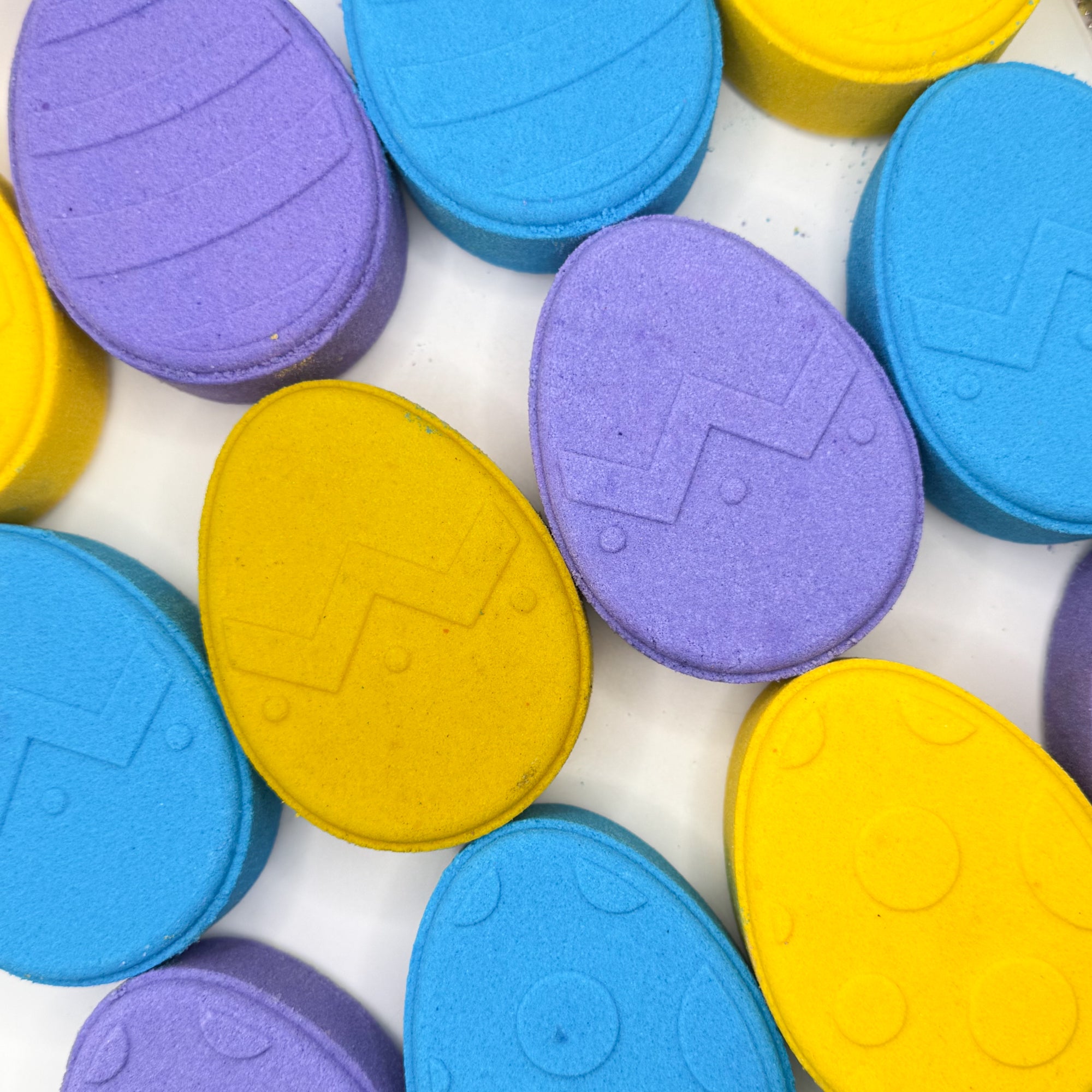 Yellow, blue and purple Easter Egg bath bombs kits laid out flat on a white background hand made by Rusted Acre Soap Co.