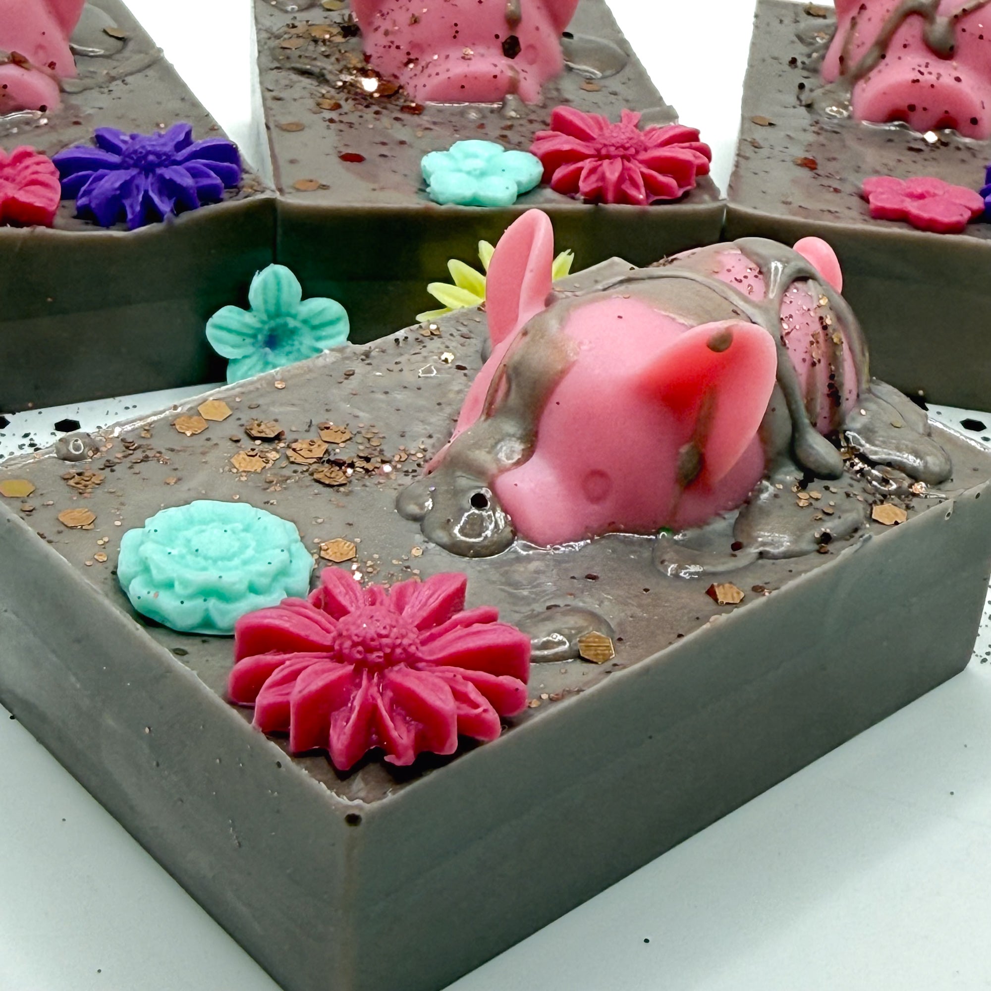 Hand made decorative soap with pink pig and flowers in a brown mud looking soap. 
