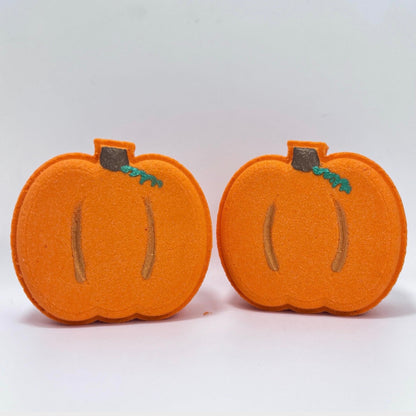 Two orange pumpkin  bath bombs with hand painted green stems on a white background.