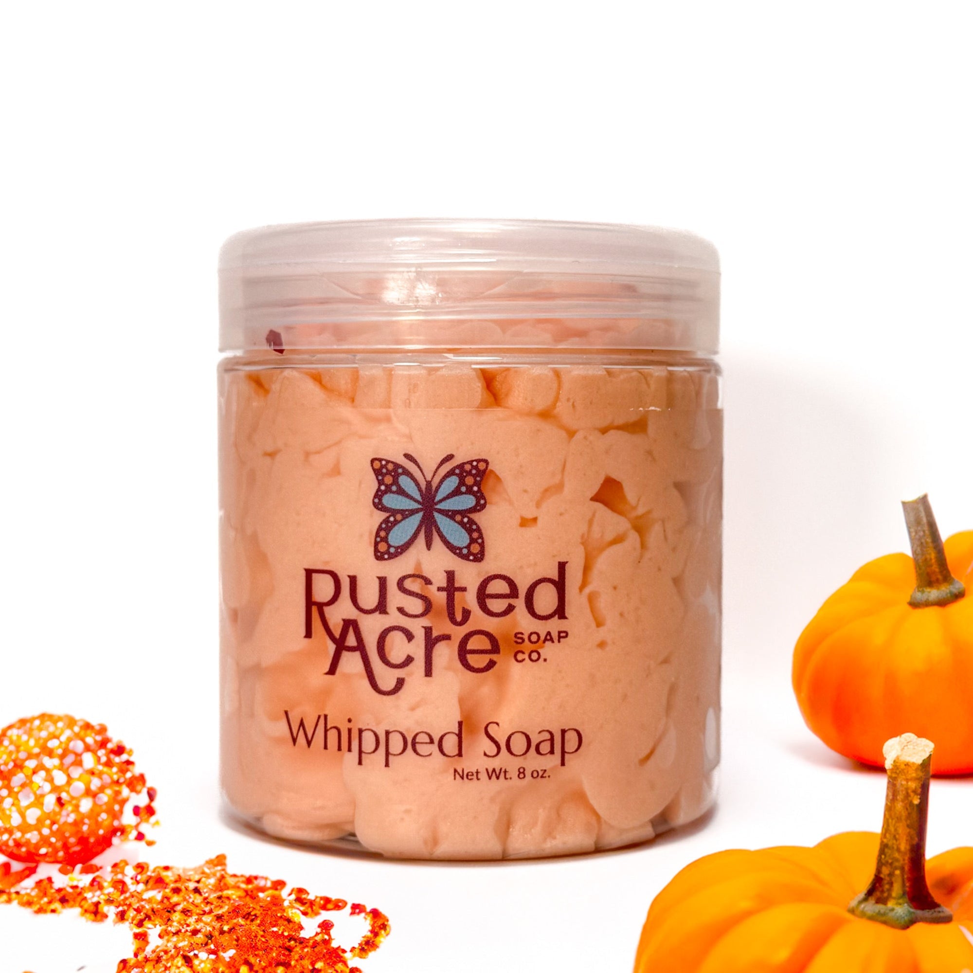 Jar of Rusted Acre Soap Company's vegan pumpkin spice whipped soap. Orange soap in a reusable plastic jar in a lifestyle setting. 