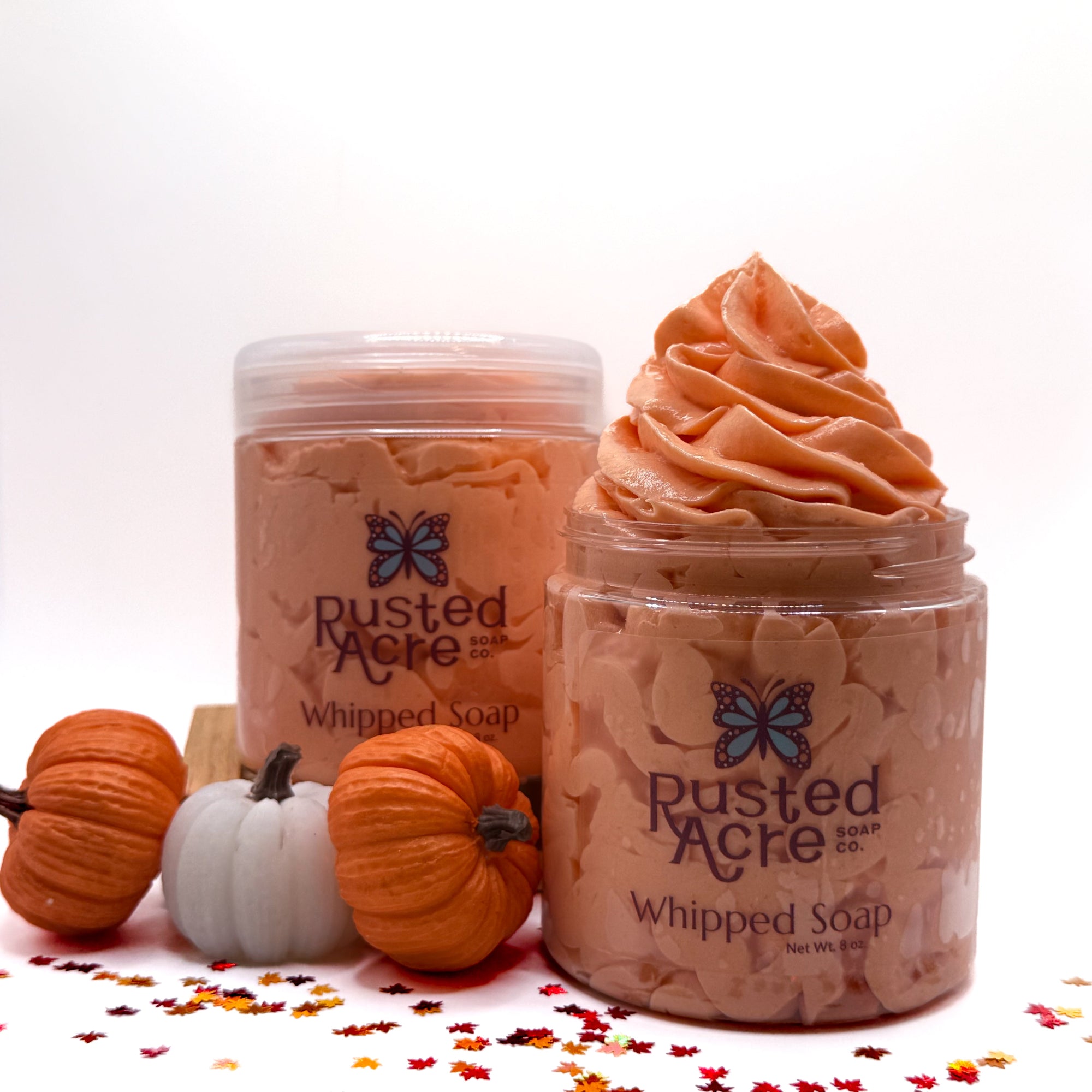 Two jars of Rusted Acre whipped soap with pumpkins and fall leaves on a white background