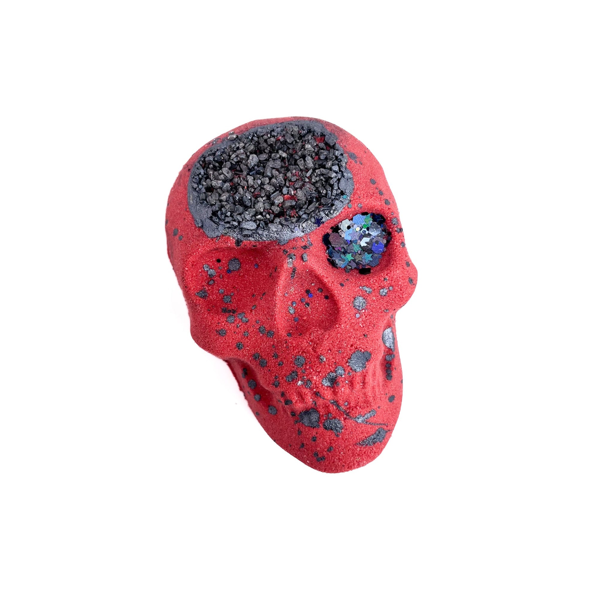A red skull shaped bath bomb with black dusted Epsom salt embedded into the forehead.  Black biodegradable glitter in left eye splattered with black mica.