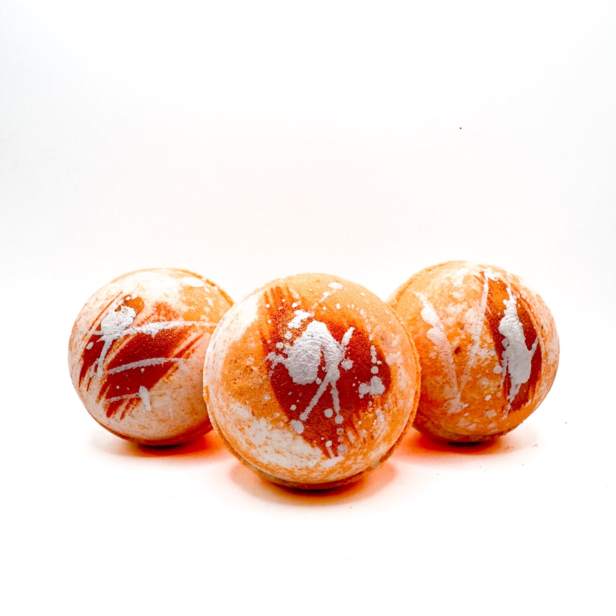 Three round hand painted orange and withe swirled bath bombs  scented with creamy orange vanilla scent. Handmade by Rusted Acre Soap Company. 