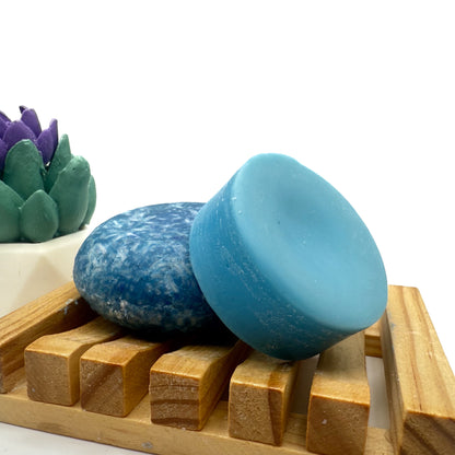 Blueberry Kiss zero waste Shampoo and Conditioner bar on a wood soap dish with a white background standing on side.