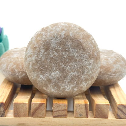 Three tan zero waste rice protein shampoo bars on a wooden surface with a white background