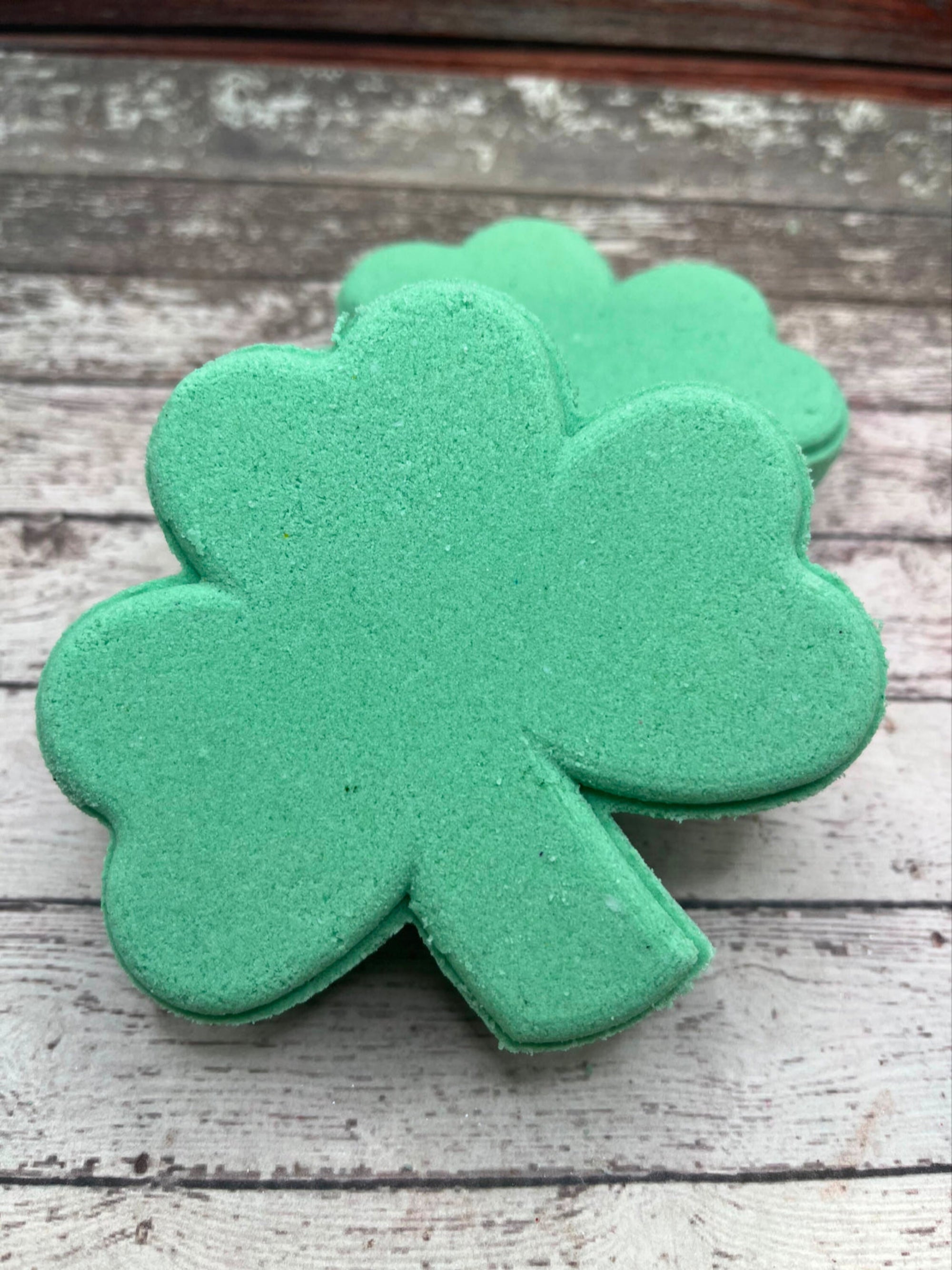 Two green shamrock bath bombs handmade by Rusted Acre Soap Company with a surprise inside.