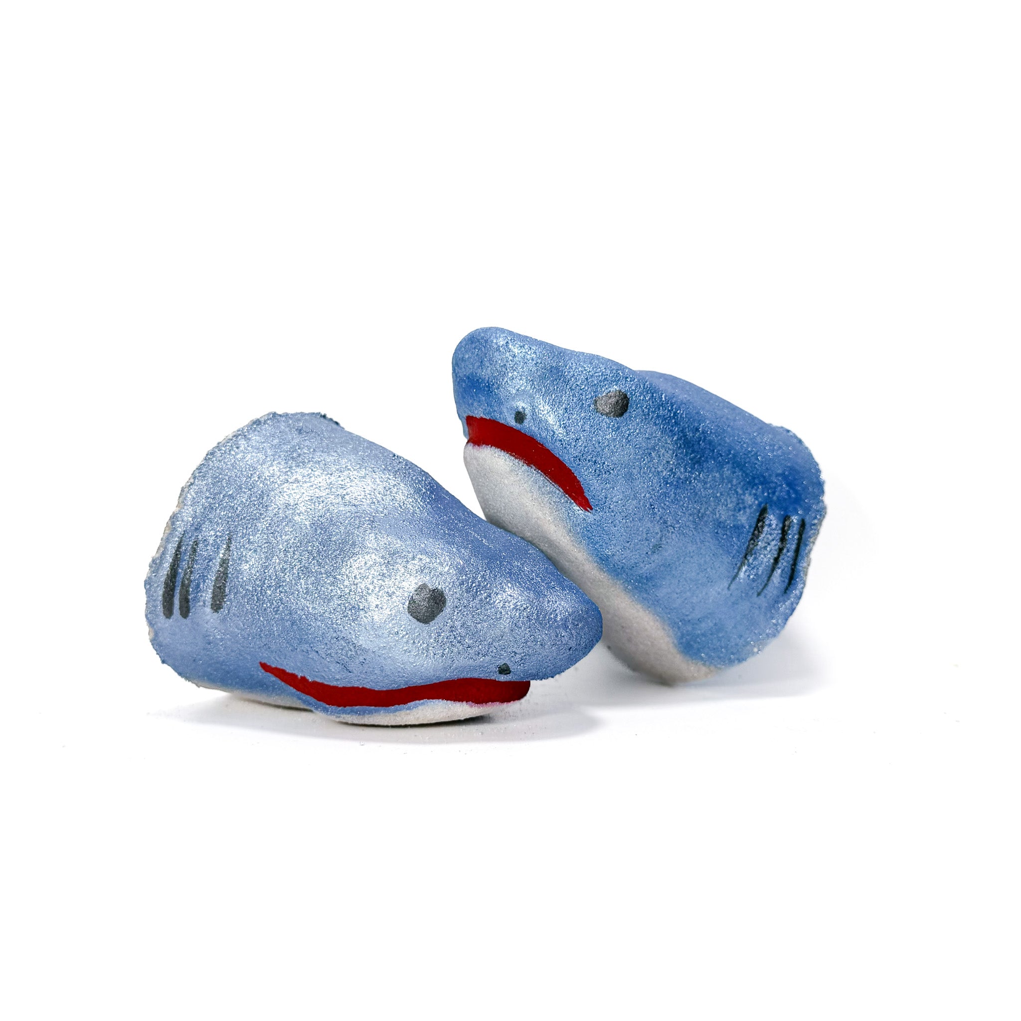 Two shark bath bomb from Rusted Acre Soap Co. facing upright. Hand-painted blue on top with black eyes and gills, and a red mouth.