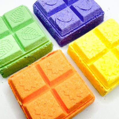 Four orange, yellow, green, purple square shower steamer on a white background 
