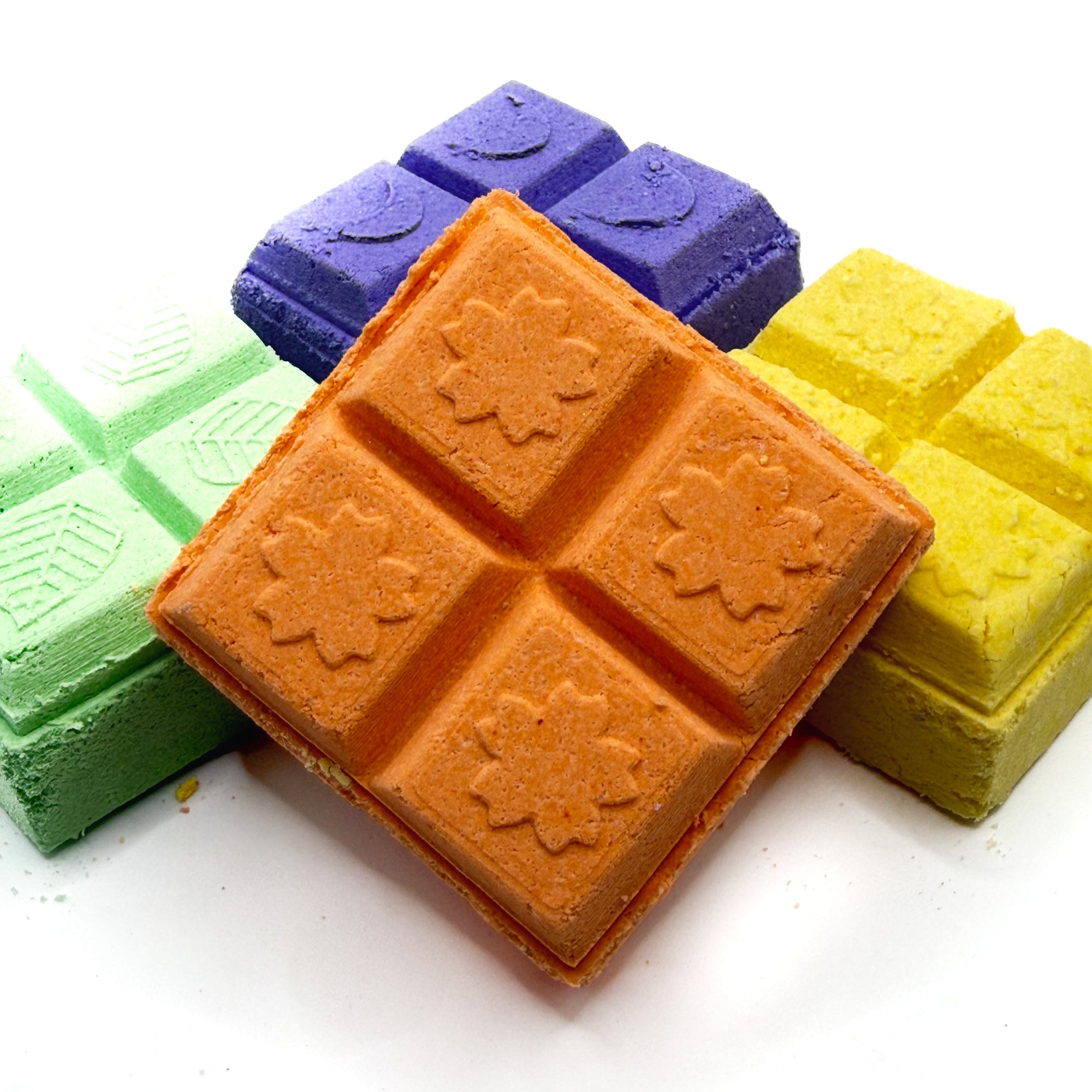 Orange dream square shower steamer with other with yellow and green shower steamers in the background on a white background 