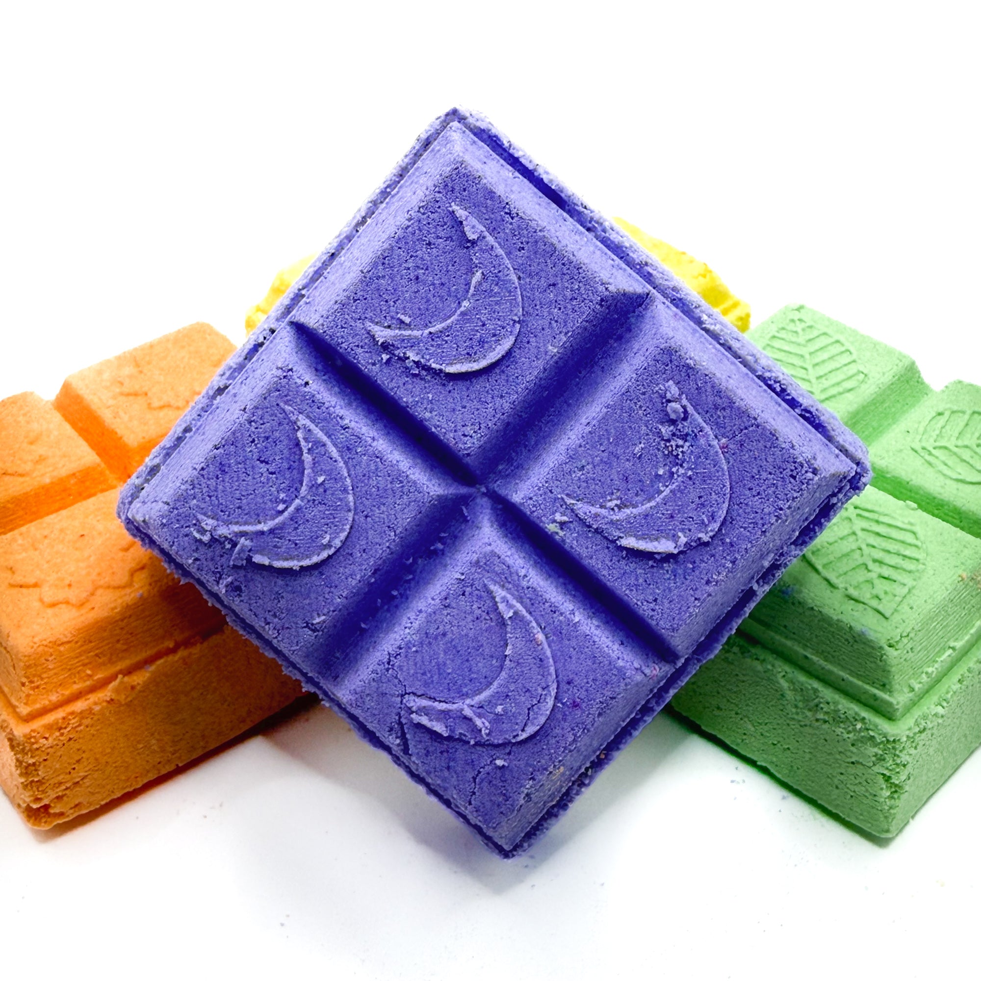 Purple lavender square shower steamer with other with orange and green shower steamers in the background on a white background 