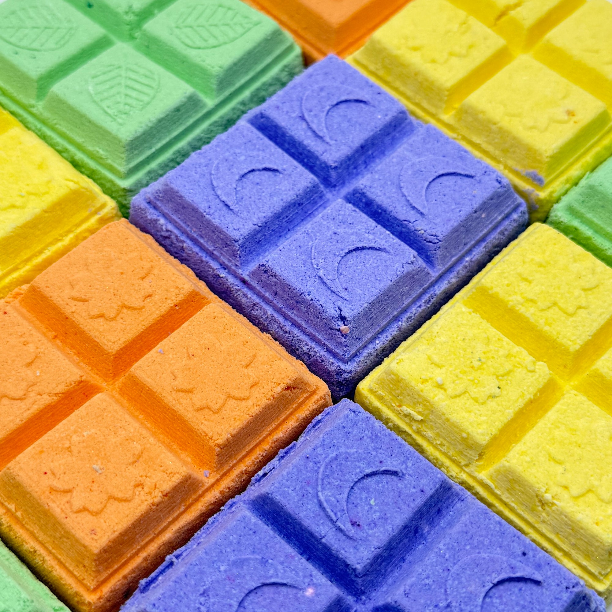 Multiple square shower steamers. Colors are yellow, green, blue, purple, orange.