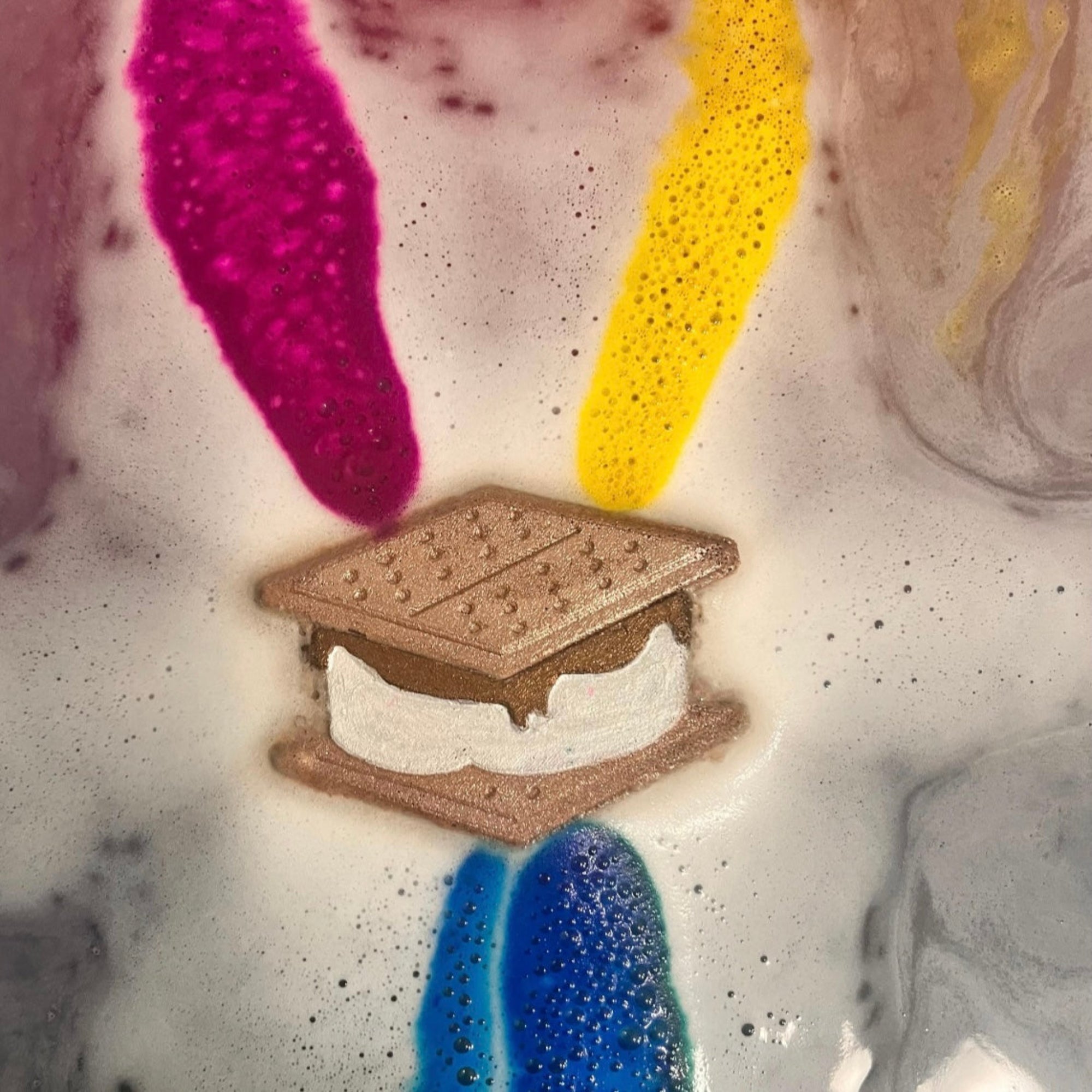 S'mores bath bomb with colorful swirls fizzing out.