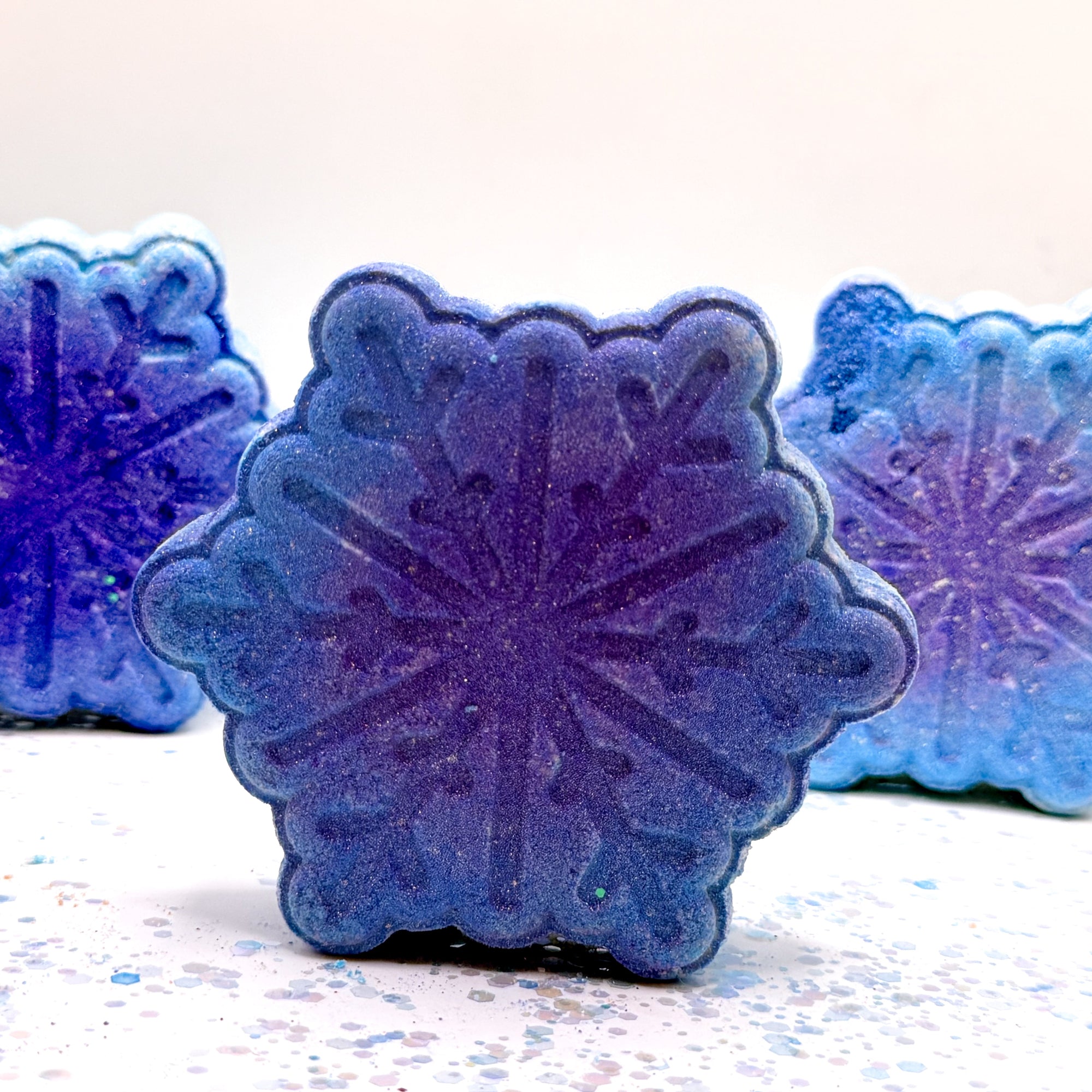 Blue snowflake shaped bath bombs on a white background