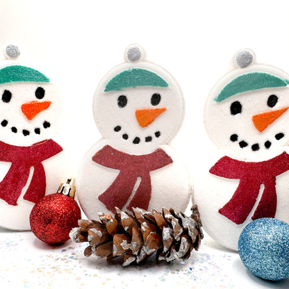 Three handmade snowman bath bombs with red scarves, green hats, and orange noses on a white background.