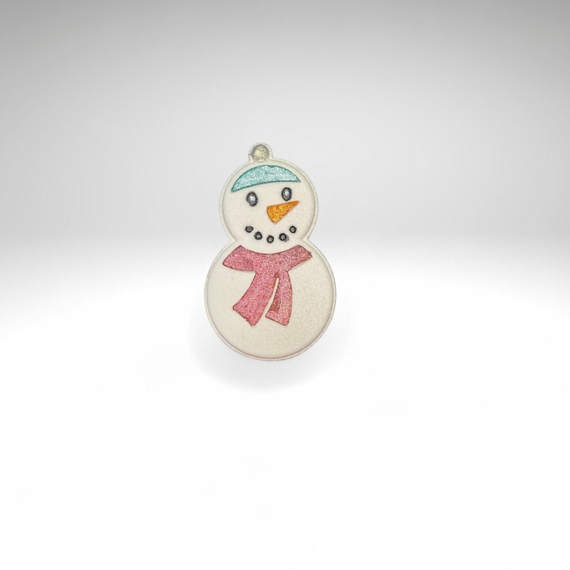One white snowman shaped bath bomb from Rusted Acre Soap Co. Hand-painted with a blue hat, snowman face and a red scarf. 