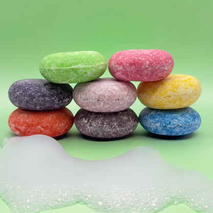 Multiple zero waste shampoo bars stacked on top of each other with foam on the counter. 