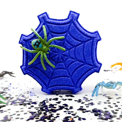One white spider web shaped bath bomb with a black spider on top