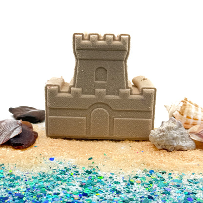 Handmade sandcastle bath bomb with decorative shells for props and glitter on a white background