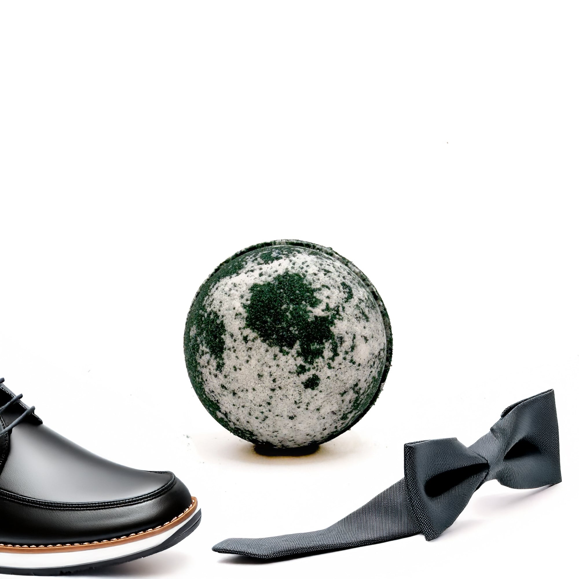 Black and white Tuxedo Bath Bomb, hand-painted with a sleek design, held in hand, made by Rusted Acre Soap Co staged in a lifestyle setting.