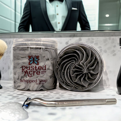 Two Jars of tuxedo whipped soap made by Rusted Acre Soap Company in a bathroom with razor.