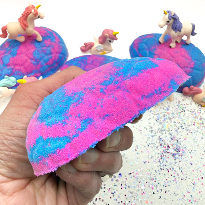 Side view of Rusted Acre Soap Co's Unicorn Egg bath bomb with unicorn figures on a glittery surface.