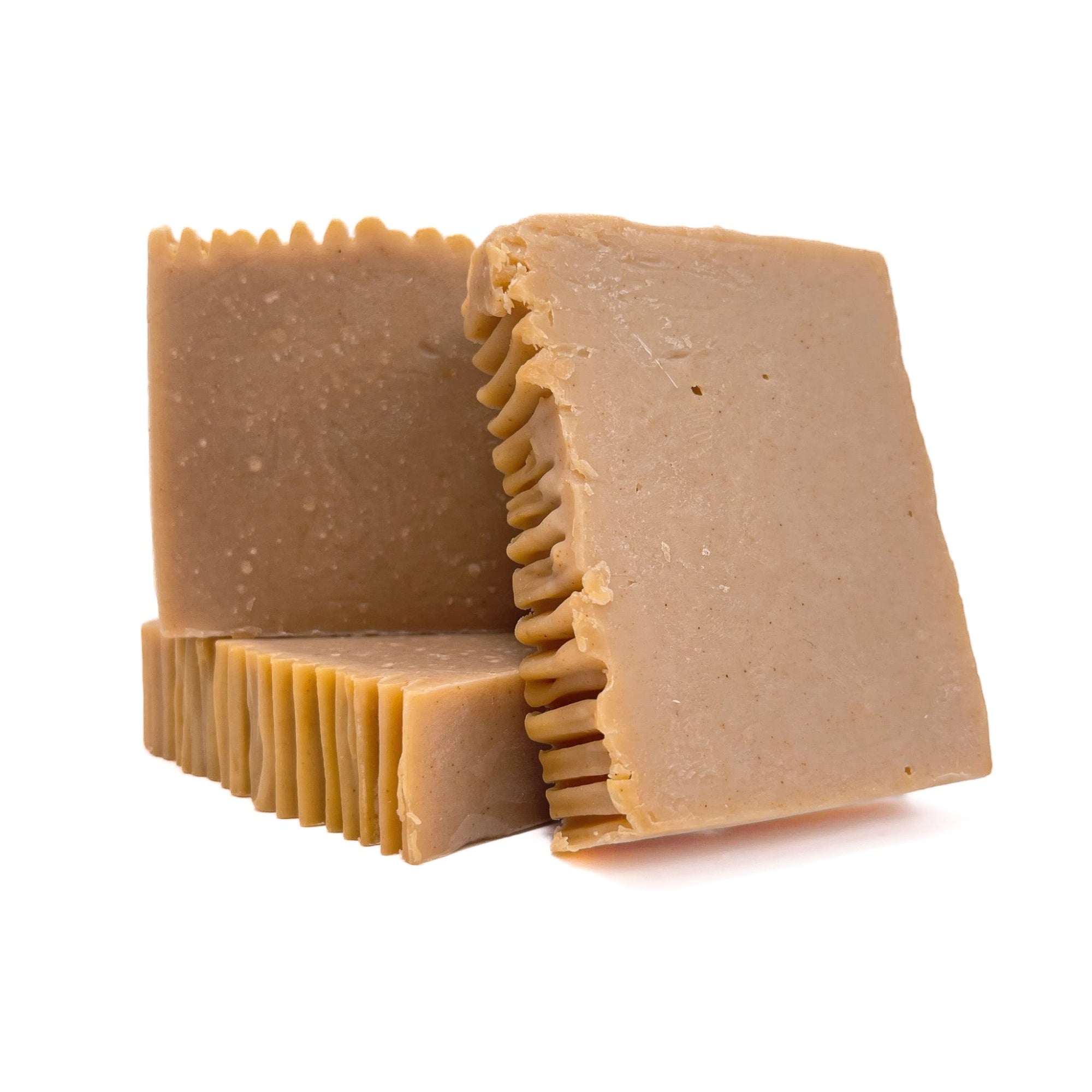 Three bars of creamy yellow colored handmade soap from Rusted Acre Soap Co. One flat and two upright showing texture. 