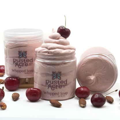 Three jars of light red cherry almond whipped soap with cherries and nuts on a white background.