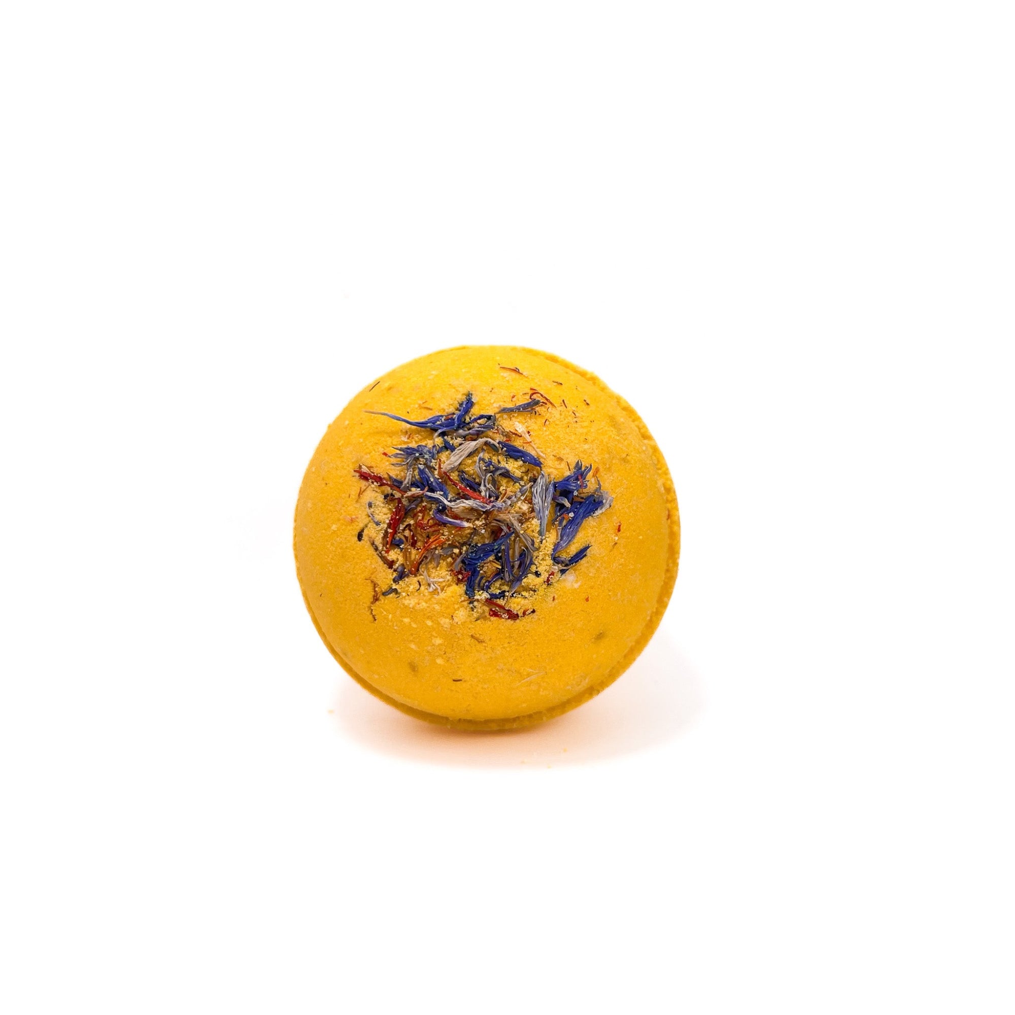 A round yellow bath bomb with red and blue cornflower petals embedded in the top.