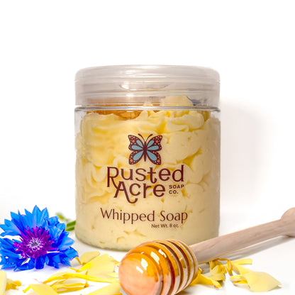 Jar of Rusted Acre Soap Company's vegan wildflower honey whipped soap. Yellow soap in a reusable plastic jar in a lifestyle setting. 