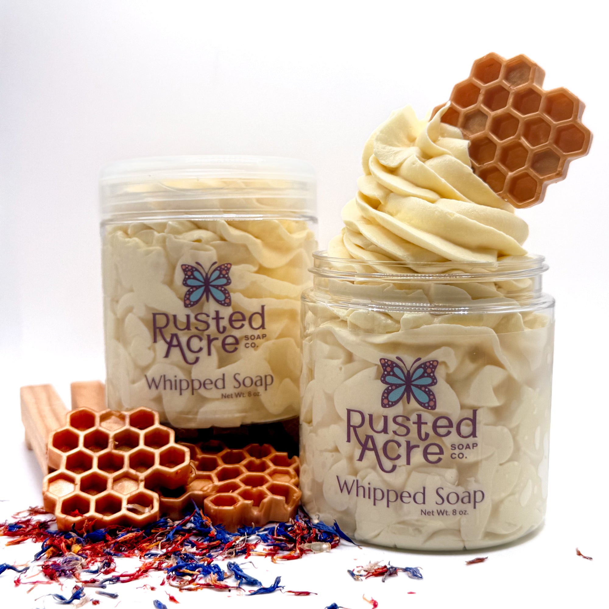 Two jars of Rusted Acre wildflower honey Whipped Soap with honeycomb  on a white background and dried wild flowers