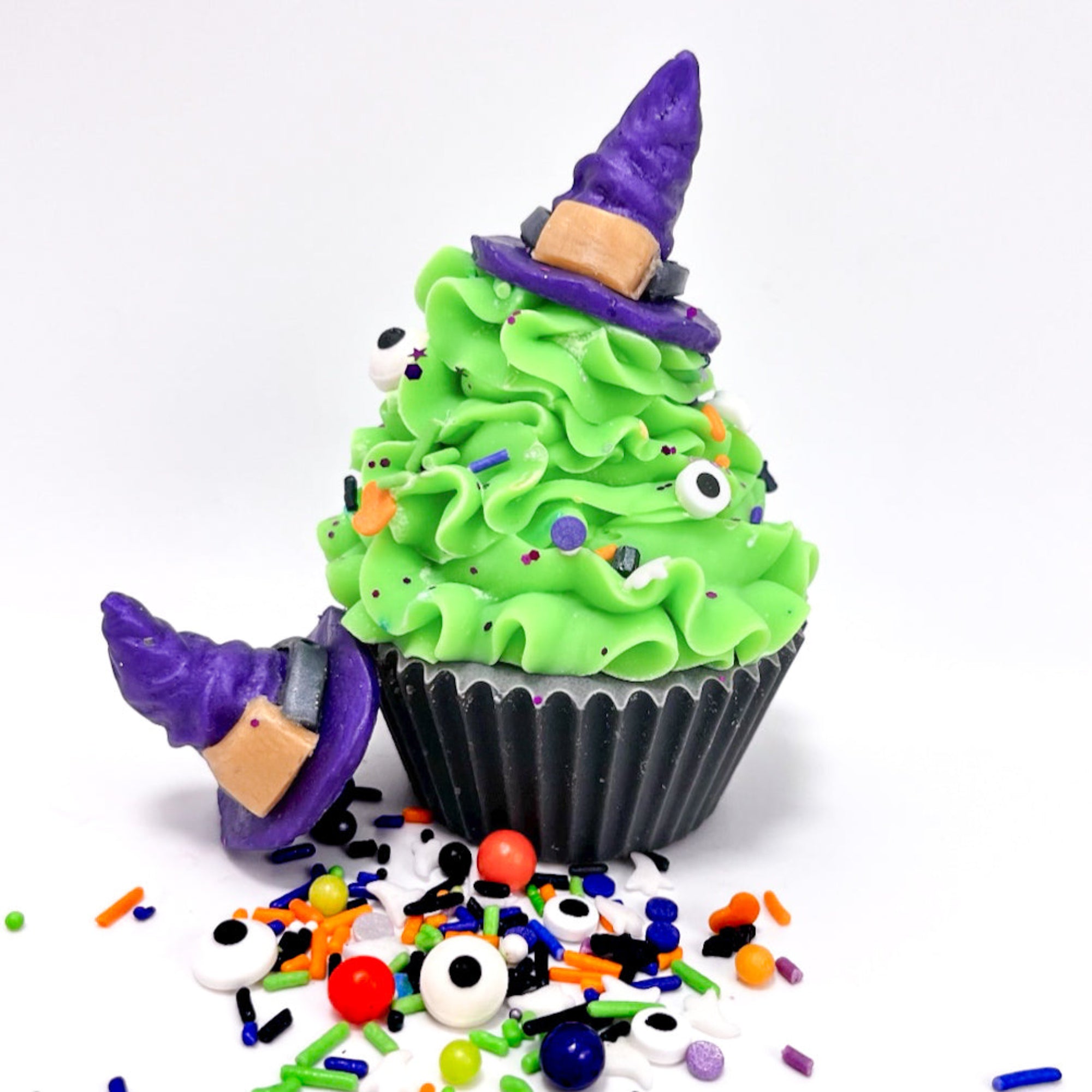 Halloween-themed cupcake soap with green frosting, purple witch hat, and colorful sprinkles on a white background.