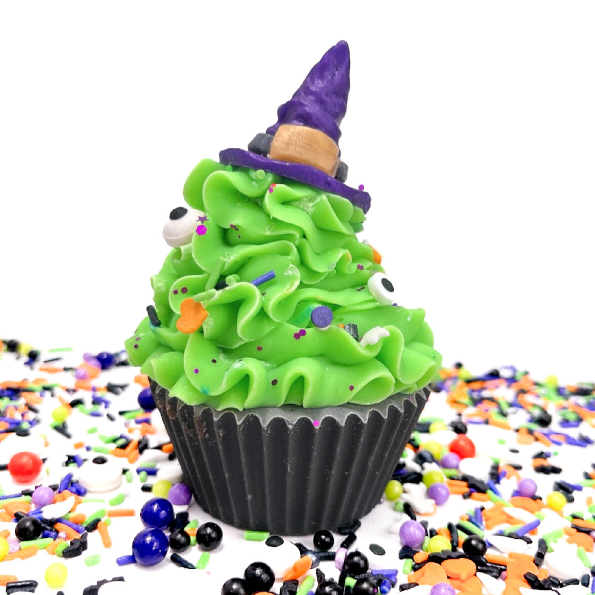 Green frosted cupcake soap with a witch hat on a white background with Halloween sprinkles.