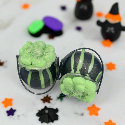 Two black cauldrons filled with green bath bomb, topped with green bubble frosting from Rusted Acre Soap Co.
